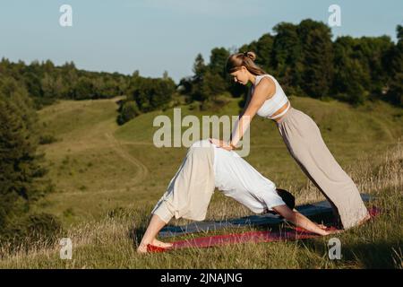 Young Adult Couple, Man and Woman Practicing Yoga Outdoors with Scenic Landscape on the Background Stock Photo