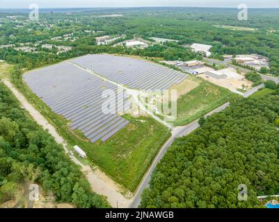Aerial view of a solar panel array installed in a lush green rice field ...