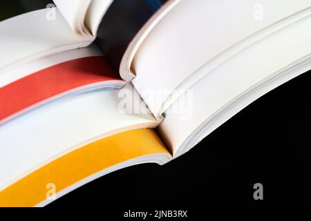 A part of a stack of open magazines on dark background Stock Photo
