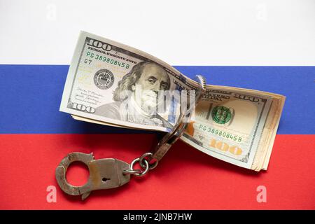 American dollars in handcuffs against the background of the flag of Russia, sanctions in Russia, business and finance, the aggressor country Stock Photo