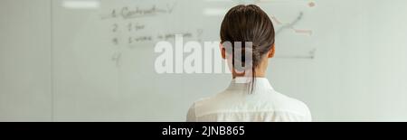 Business woman looks at flipboard with charts and plans. View from the back Stock Photo