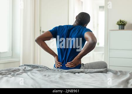 Unrecognizable African American Guy Touching Aching Lower Back In Bedroom Stock Photo