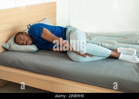 African American Young Man Sleeping On Side Lying In Bedroom Stock Photo