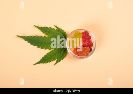 thc jelly candies, cannabis sweets drugs and green leaf on yellow background. Stock Photo