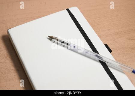 Detail of a white notebook to make notes next to a pen used to make notes. Image with copy space Stock Photo