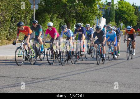 Bicycle racers in the peloton riding a lap of the Criterium, a cycling road race where the cyclists ride their bikes around a circuit on city streets. Stock Photo