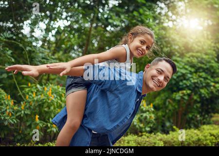 Their bond is as bright as a summers day. Cropped portrait of a happy father piggybacking his daughter at the park. Stock Photo