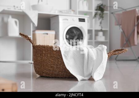 Wicker basket with clean towel in laundry room, closeup Stock Photo