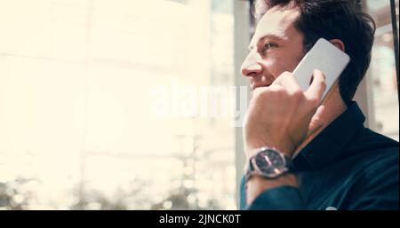Sealing the deal in a single phone call. a handsome middle aged businessman taking a phonecall while standing in the workplace. Stock Photo