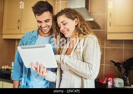 Keeping in touch with our friends. a loving couple using a digital tablet together at home. Stock Photo