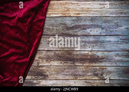 Red fabric velvet table cloth on empty wooden table background with copy space. Stock Photo