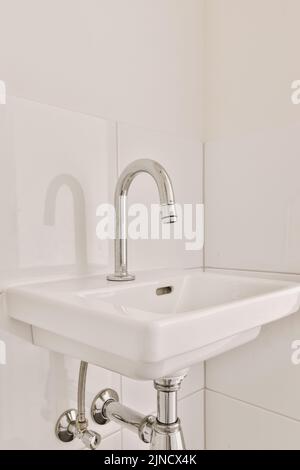 Sink with tap and liquid soap hanging on tiled wall in contemporary restroom at home Stock Photo