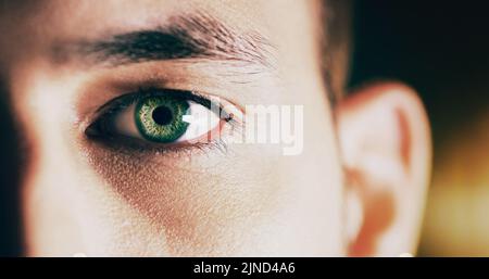 Looking at the future. Closeup shot of man opening his eyes against a dark background. Stock Photo