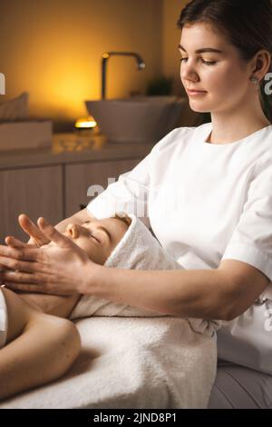 Cosmetologist making manual relaxing rejuvenating facial massage for face in beauty salon. Spa, resort, beauty and health concept. Facial massage Stock Photo
