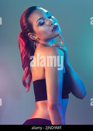 Shes from another world. Studio shot of a beautiful young woman posing against a multi colored background. Stock Photo