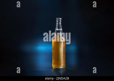 unlabeled bottle of lemonade on a dark blue background. The bottle of kambucha is fogged up. Cold bottle of fermented lemonade Stock Photo