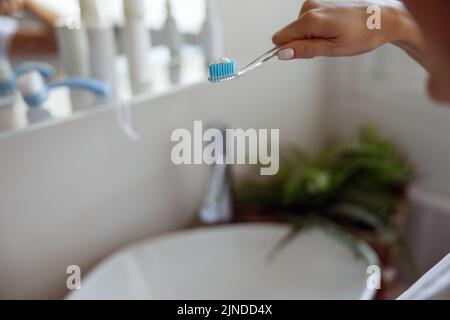 Close up of blue toothpaste on toothbrush in hand of Caucasian woman. Cleaning teeth. Stock Photo