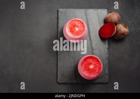 Two cups of hot beet coffee latte on a dark background. A trendy, healthy drink. An alternative to caffeine. Top view and copy space. Stock Photo