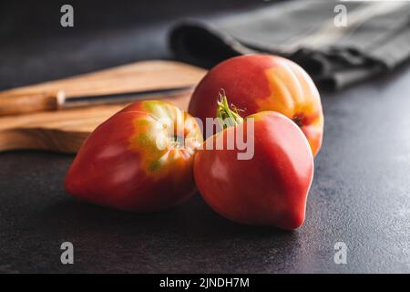 Bull heart tomatoes on a black table. Stock Photo