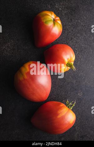 Bull heart tomatoes on a black table. Top view. Stock Photo