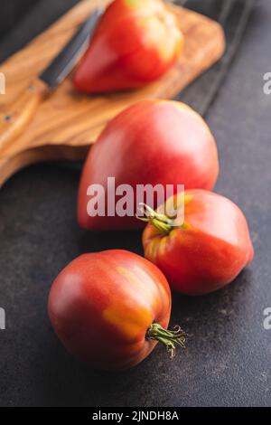Bull heart tomatoes on a black table. Stock Photo