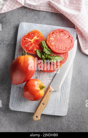 Sliced bull heart tomatoes on a cutting board. Top view. Stock Photo