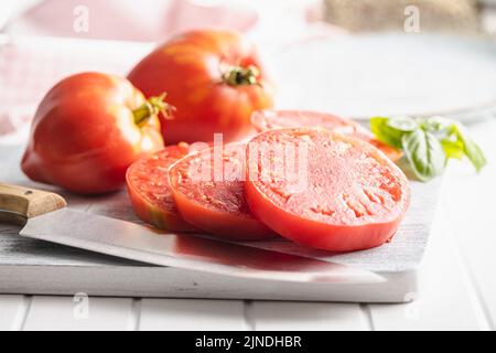 Sliced bull heart tomatoes on a cutting board. Stock Photo