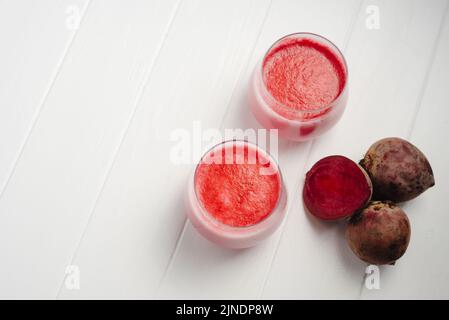 Two cups of hot beet coffee latte on a white wooden background. A trendy, healthy drink. An alternative to caffeine Stock Photo