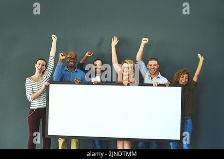 Happy, diverse and cheering marketing team with a blank card, poster or billboard with copyspace in studio on a grey background. A group of smiling Stock Photo