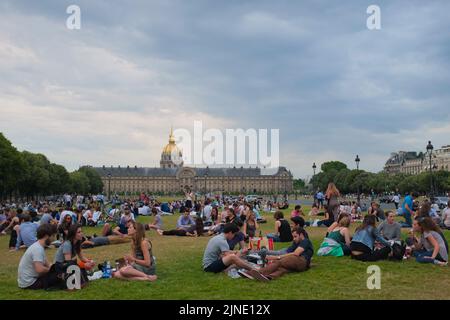 Groups of people, mostly tourists, chill on the grass near the Les Invalides (House of the Disabled). Beautiful summer day outdoor in Paris, France. Stock Photo