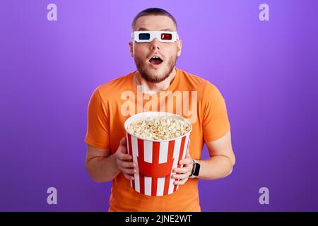 Young caucasian man in 3d glasses eating popcorn Stock Photo