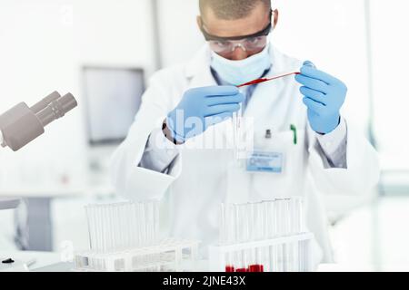 A scientist conducting an experiment on a covid vaccine in a lab mixing chemicals in a test tube. A medical researcher working in a laboratory testing Stock Photo