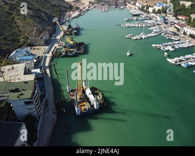 Floating crane dredging barges working on the construction of a marina. Aerial top view Stock Photo