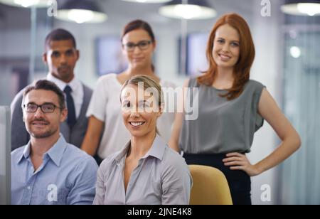 Group portrait of smiling businesspeople with computer working together on project, innovating design or collaborating on company vision. Smiling Stock Photo