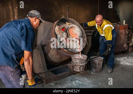 Foundry workers in a small family foundry in Perth, Western Australia pouring molten aluminium from a furnace Stock Photo