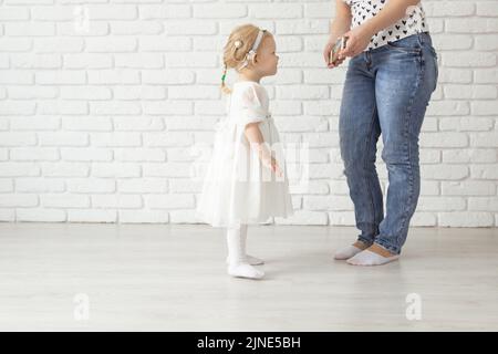 Child with cochlear implant hearing aid having fun with mother in room background with copy space and place for advertising - diversity and deafness Stock Photo