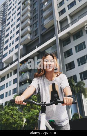 Happy pretty young woman walking with her bicycle in the street Stock Photo