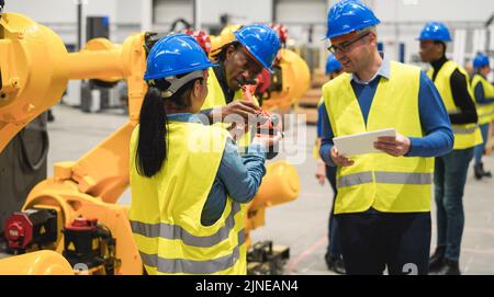 Multiracial engineers working inside robotic factory - Focus on woman helmet Stock Photo