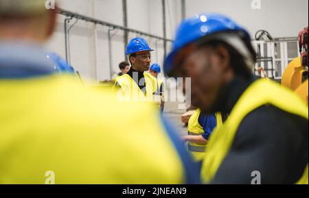 Multiethnic engineers working inside robotic factory - Focus on african man holding cup of coffee Stock Photo