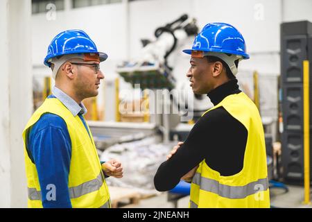 Multiethnic engineers working inside robotic factory - Focus on right man face Stock Photo