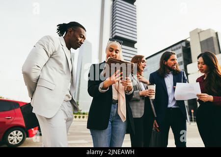 Multiracial business people working outdoor from office building - Focus on arabian woman hands holding digital tablet Stock Photo