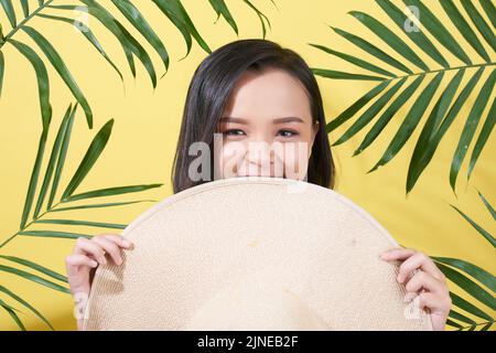 Attractive Asian girl hugging behind big straw hat Stock Photo