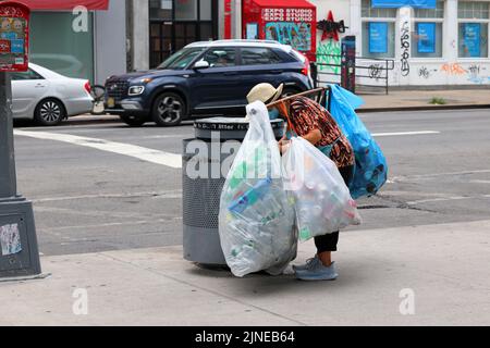 An elderly Asian person reaches into a New York City trash bin for recyclables. Many people, especially elderly Chinese, are dependent on the ... Stock Photo