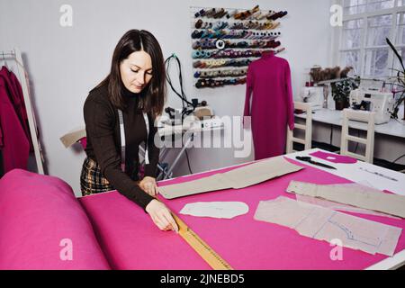 Seamstress working with sewing pattern on table in tailor shop Stock Photo