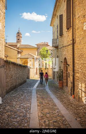 Couple walking a small alley in Castell'Arquato in a sunny day, Piacenza, Italy Stock Photo