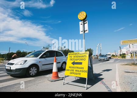 Paphos, Cyprus - Oct 29, 2014: Pedestrians can use walk side opposite sign in city of Paphos with cars driving on the street Stock Photo