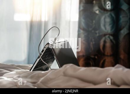 Laptop on the bed with USB charging port connected Stock Photo