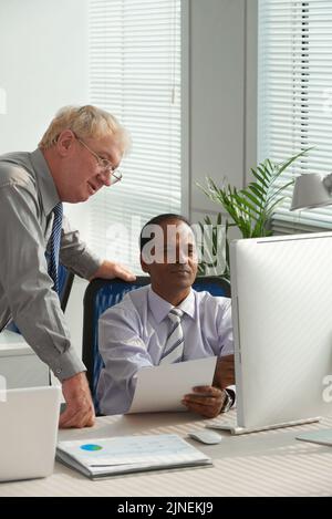 Cheerful multiethnic business colleagues reading information on computer screen Stock Photo