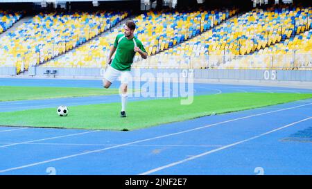 full length of young and bearded football player in uniform warming up at stadium,stock image Stock Photo