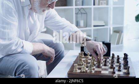 partial view of senior bearded man playing chess at home in living room,stock image Stock Photo